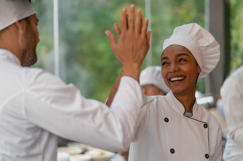 Food handler smiling and sharing a high-five with their manager