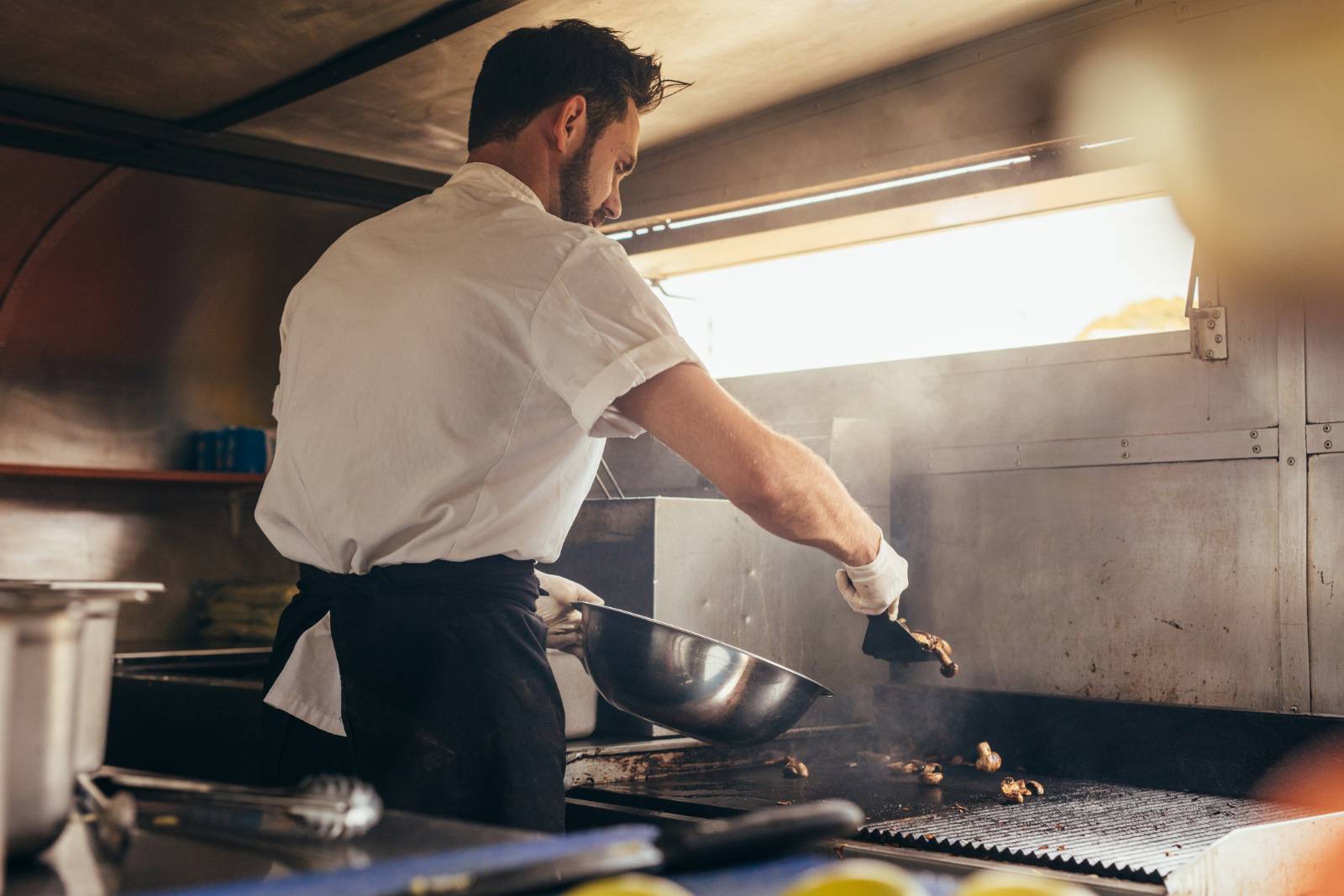 Chef wearing gloves working over a grill